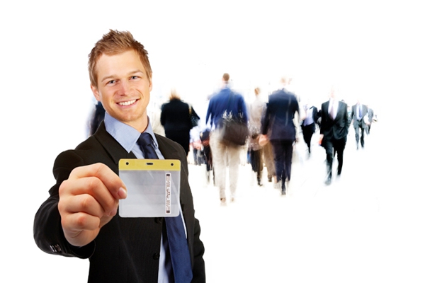 Young professional man wearing suit and tie holding up a Convention Strategy RFID Badge